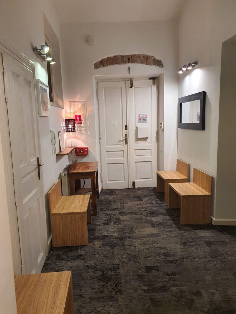 Poczekalnia z drewnianymi ławkami i ceglanym łukiem